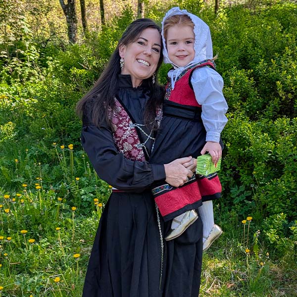Helen with daughter in traditional wardrobe standing in a green field.